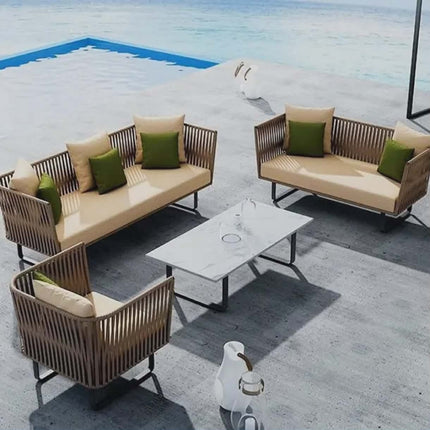Outdoor patio furniture set with beige cushions and green pillows on a concrete patio.