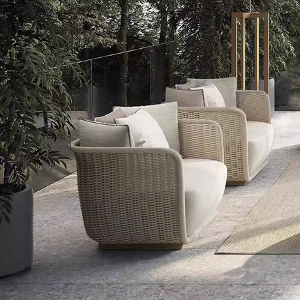Outdoor patio furniture set with wicker chairs and cushions on a stone patio.
