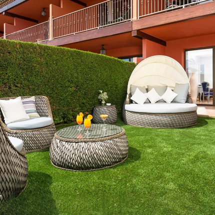 Outdoor patio set with wicker chairs and table on a grassy area.