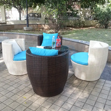 Outdoor patio set with wicker chairs and table on a paved area.