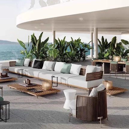 Modern outdoor furniture set with a view of the ocean and plants.