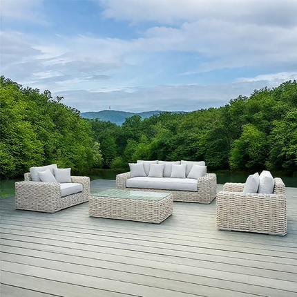 Outdoor patio set with wicker furniture on a wooden deck overlooking a forest.