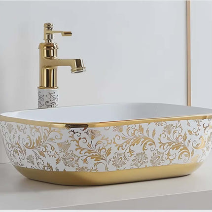 Decorative bathroom sink with gold accents and a matching faucet.
