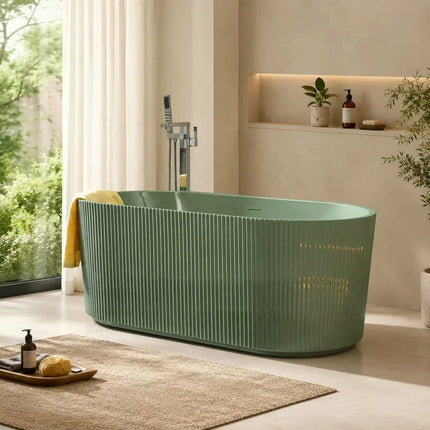 A freestanding oval bathtub in a muted sage green color with vertical fluted detailing, styled in a modern bathroom setting with a chrome faucet, a yellow towel, and a beige rug.