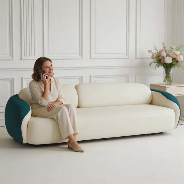 Woman sitting on a modern white and blue sofa in a stylish room with decorative wall panels and flowers.