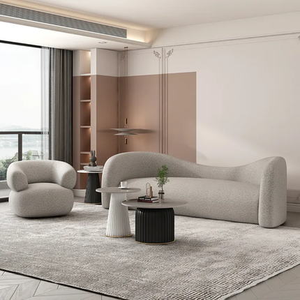 Modern living room with a gray sofa and armchair, coffee table, and decorative elements.
