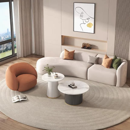 Modern living room with a white sofa, orange chair, and round coffee table.
