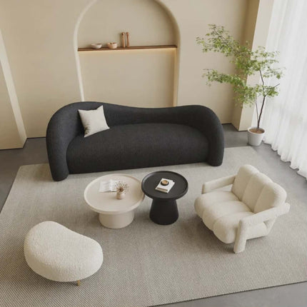 Modern living room with a black sofa, white armchair, and side tables.