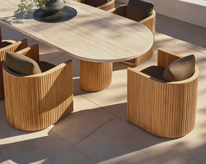 Outdoor dining set with wooden table and chairs on a patio with ocean view