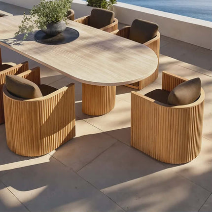 Outdoor dining set with wooden table and chairs on a patio with ocean view