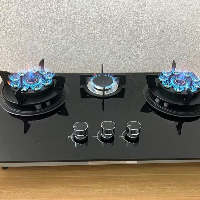 Three-burner gas stove with blue flames on a wooden surface.