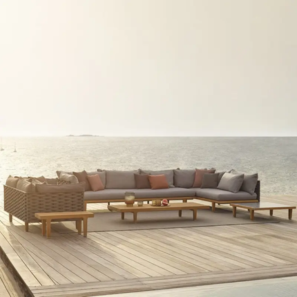 Outdoor patio furniture set with sectional sofa and coffee table on a wooden deck.