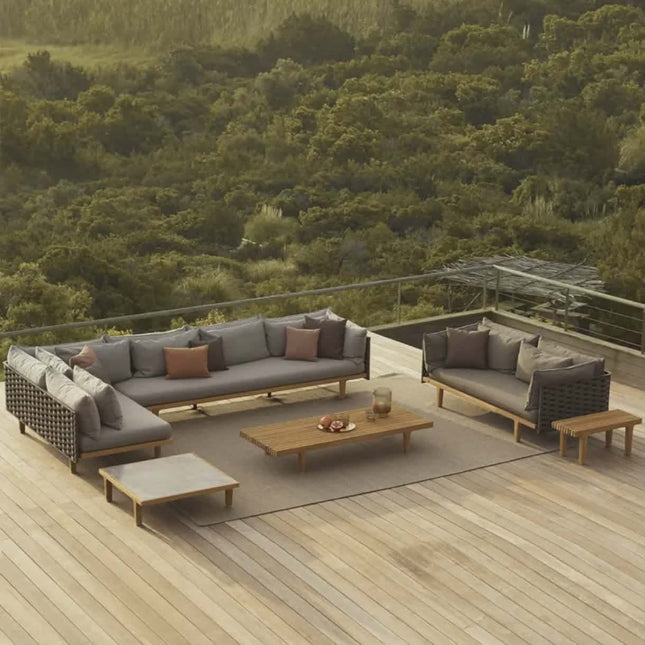 Outdoor patio furniture set with cushions on a wooden deck overlooking a forest.