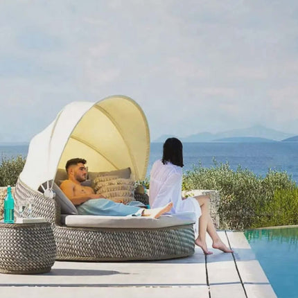 Two people relaxing on a sunbed by a pool with a scenic view.