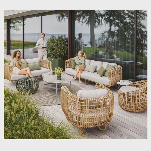Outdoor patio with wicker furniture and people sitting on a deck.