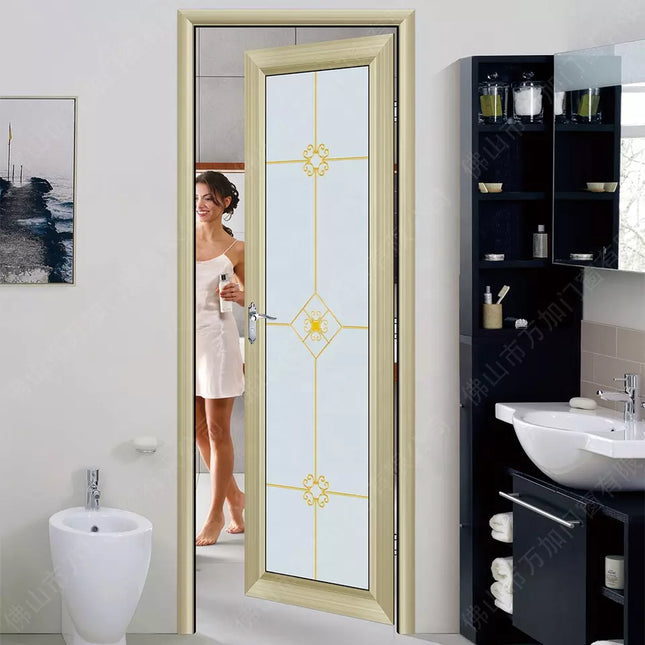 A modern style glass double swing door with a gold-colored aluminum frame, installed in a bathroom setting, with a woman standing in the doorway.