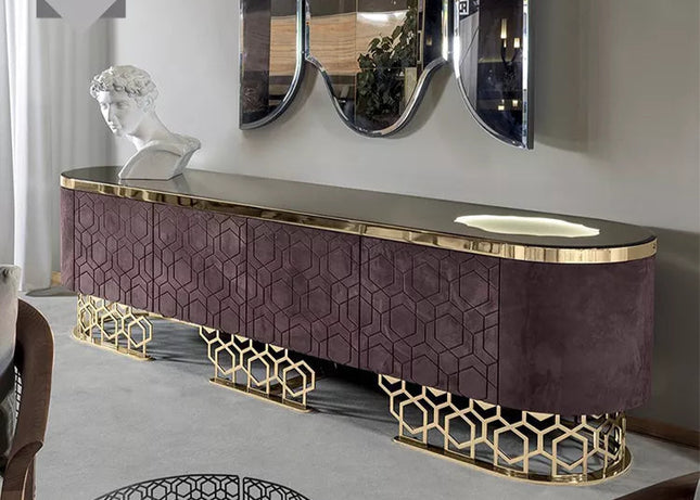 A modern TV stand with a purple and gold color scheme, featuring a flat-screen TV on top, set against a reflective wall with a large mirror behind it. The stand has a geometric pattern on the legs and a drawer for storage.