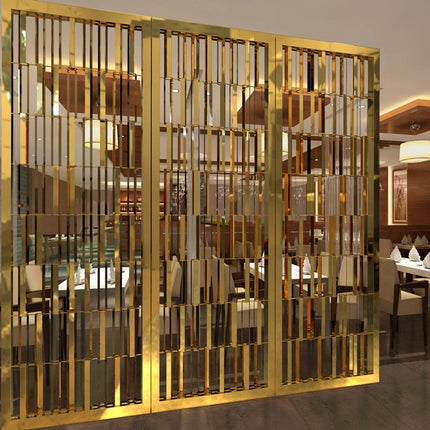 A gold-colored stainless steel room divider screen with geometric patterns, installed in a restaurant setting.
