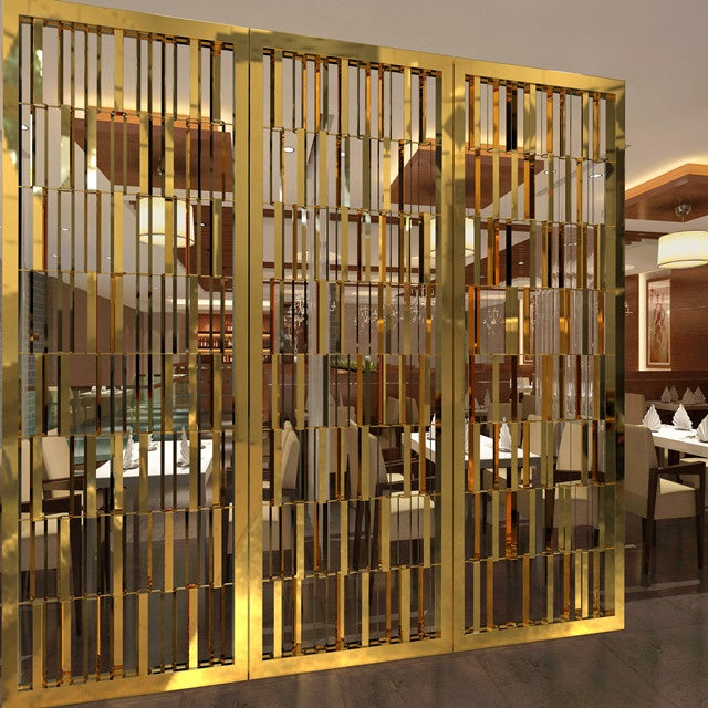 A gold-colored stainless steel room divider screen with geometric patterns, installed in a restaurant setting.