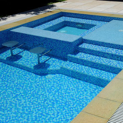 Mixed blue glass mosaic tiles in varying shades create a seamless, flowing look across pool floors, walls, steps and sunken spa areas – glossy finish enhances water reflection, delivering a bright, inviting and cohesive aquatic environment